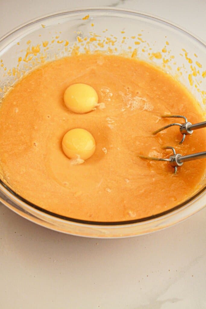Eggs being added to butter in a glass bowl.