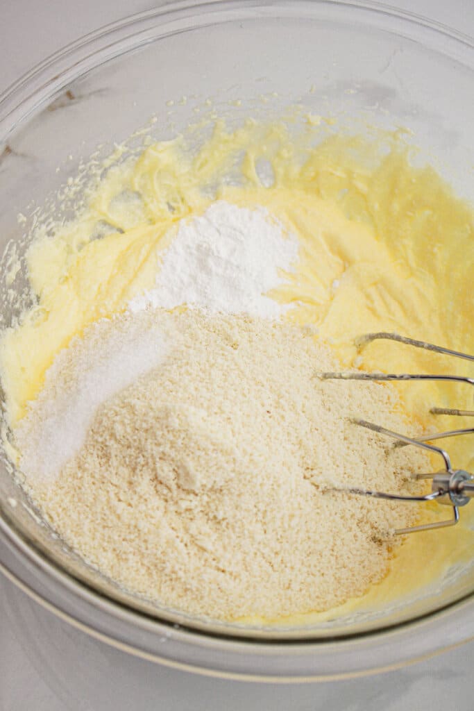 Flour being added to batter in a glass bowl.