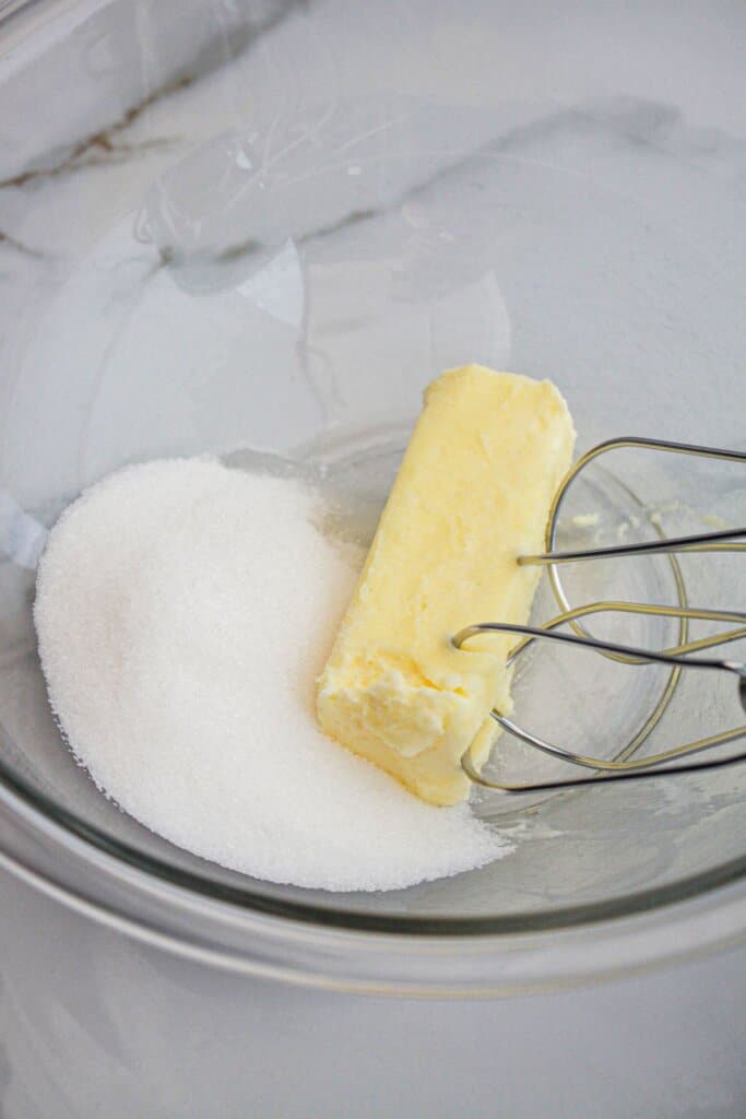 Butter and sugar in a glass mixing bowl.
