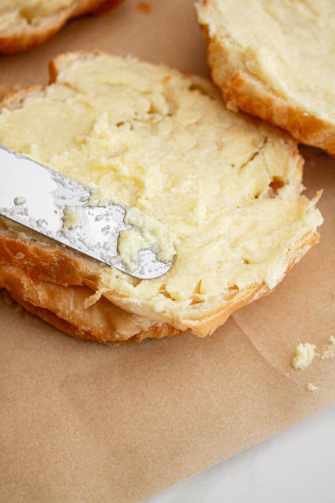 Butter being spread on crossiants.