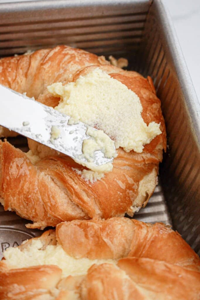 Butter being spread on crossiants.