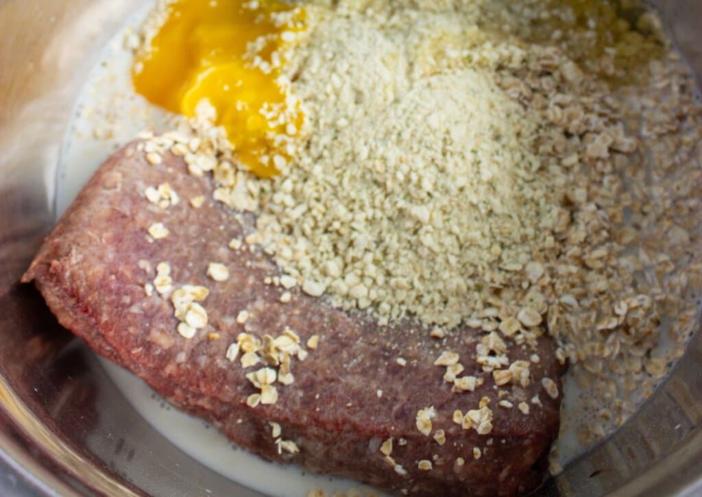 Beef and ingredients being mixed in a bowl.