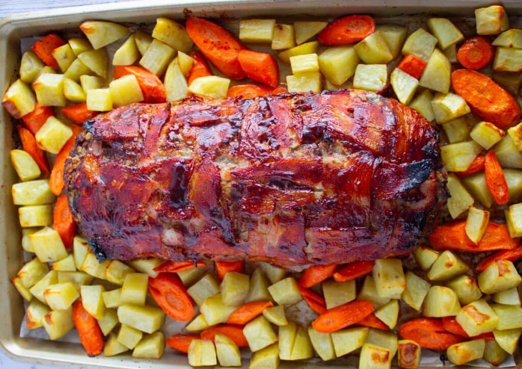Cooked meatloaf and vegetables on a baking dish.