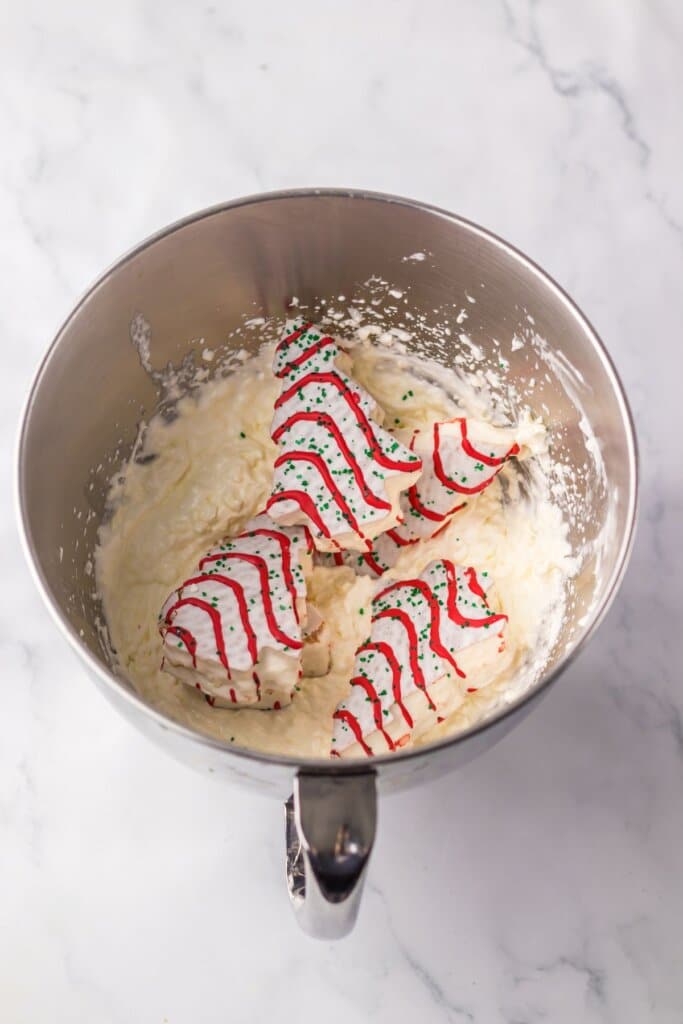Christmas tree cakes being added to a mixing bowl.
