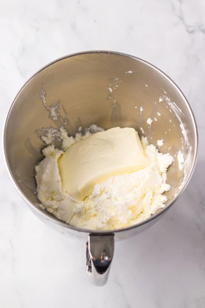 Cream cheese being mixed in a mixing bowl.