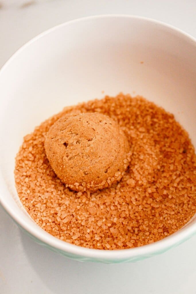Cookie dough being rolled in sugar.