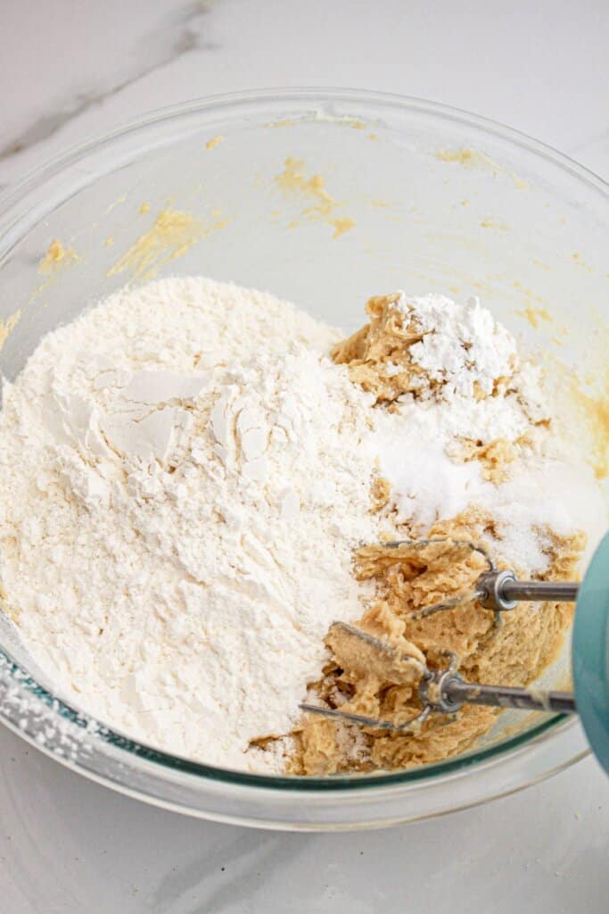 Dry ingredients being added to a glass mixing bowl.