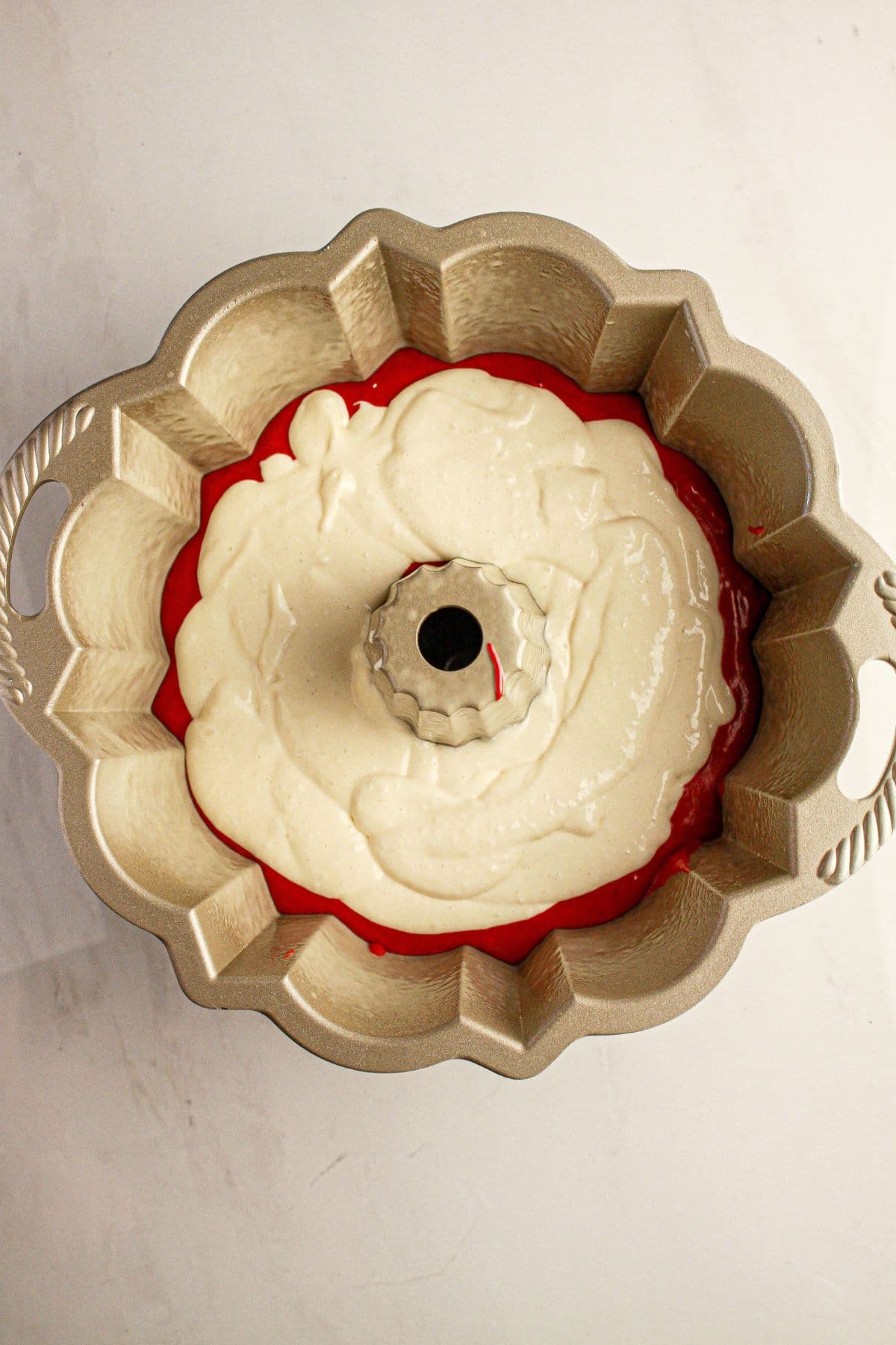 Cream cheese filling added to a cake pan.