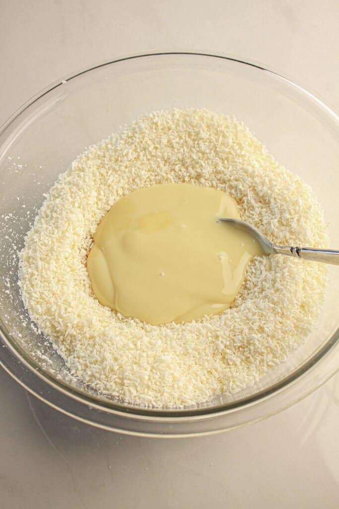 Coconut and sweetened condensed milk being mixed together.