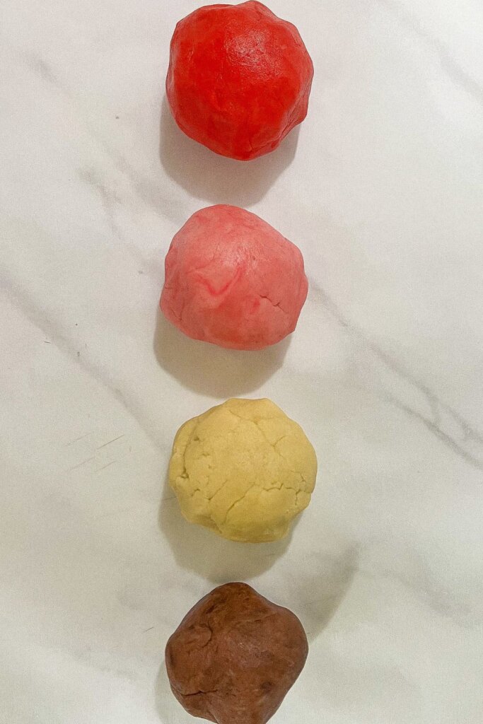 Four dough balls on a counter.
