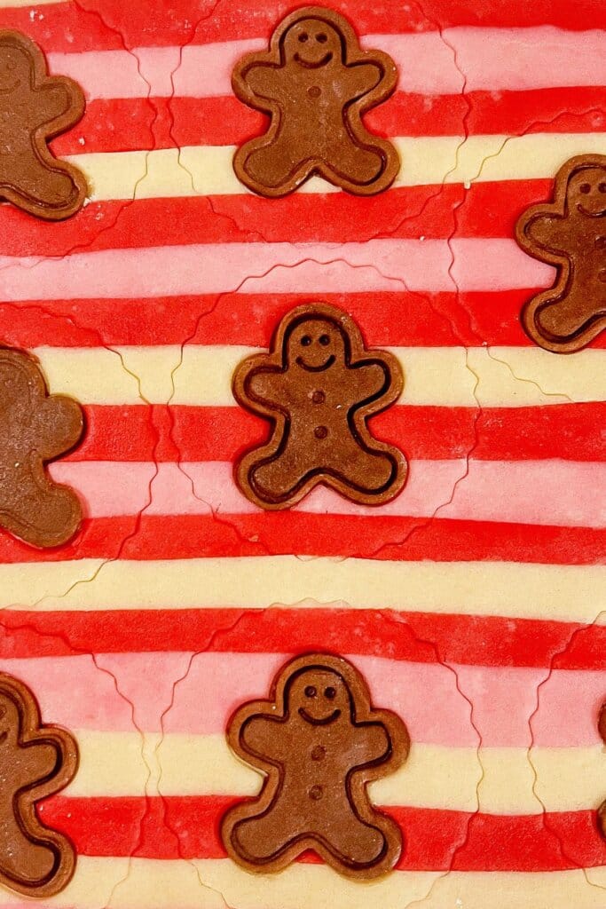 Gingerbread men being added to cookie dough.