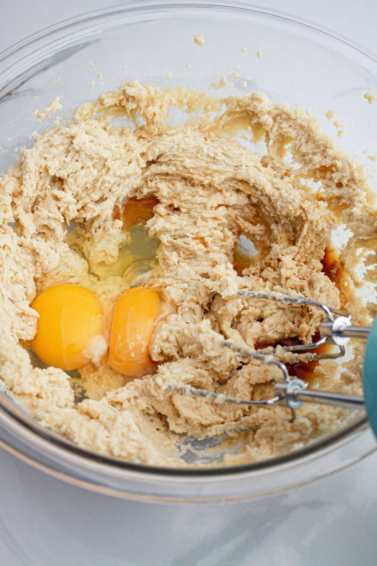 Eggs being added to dough in a mixing bowl.