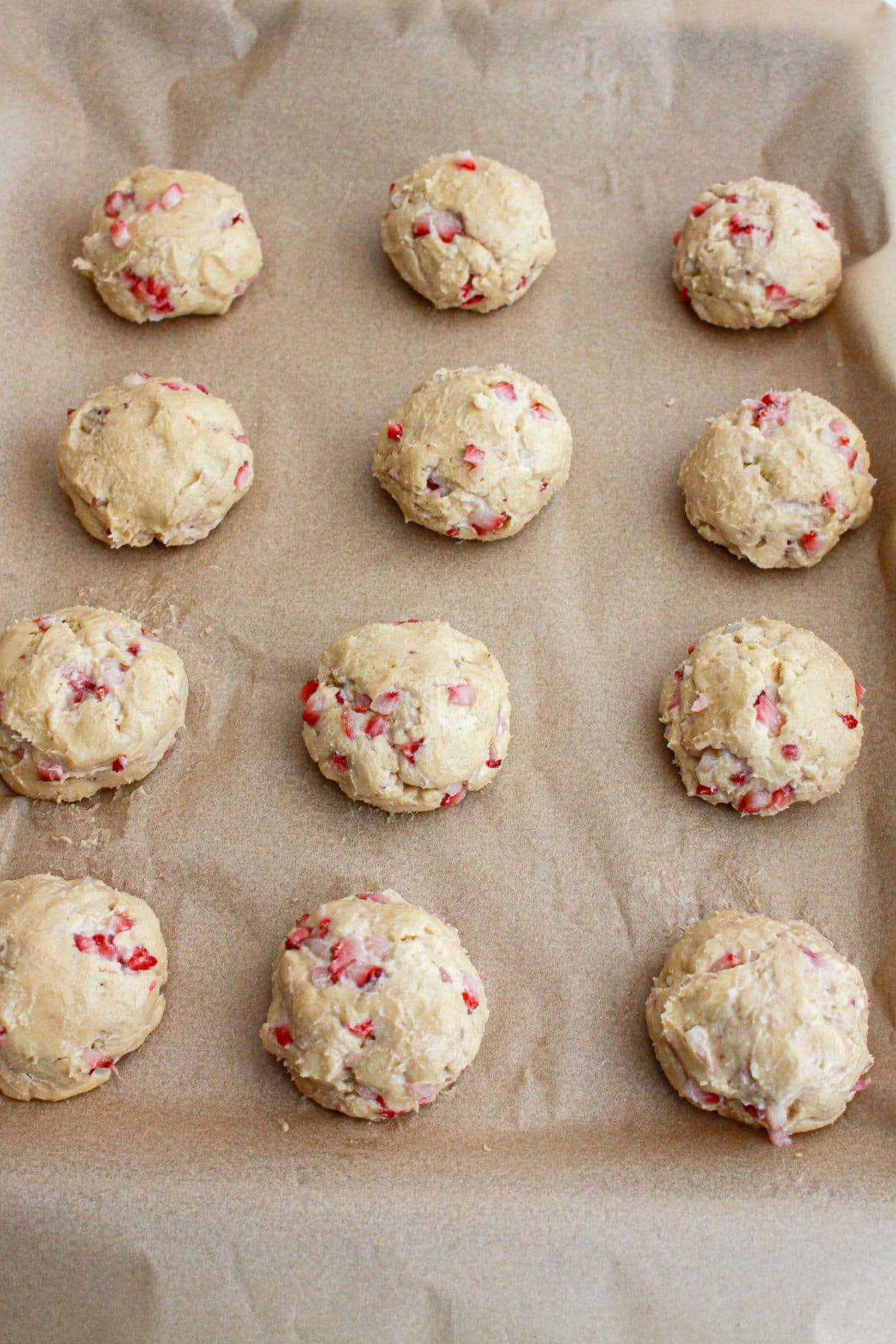 Cookie dough balls on a parchment lined baking sheet.