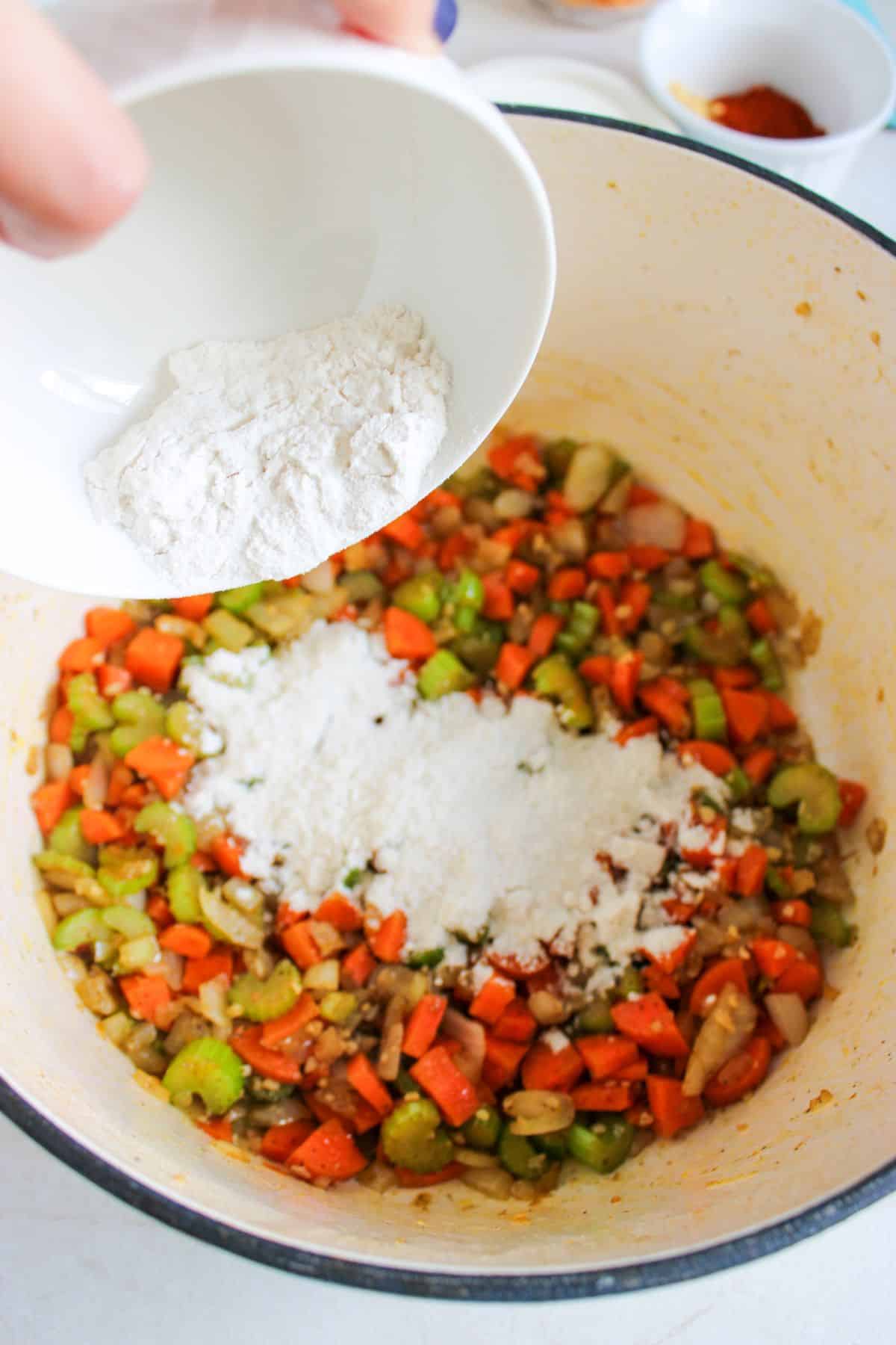 Flour being added to pot of vegetables.
