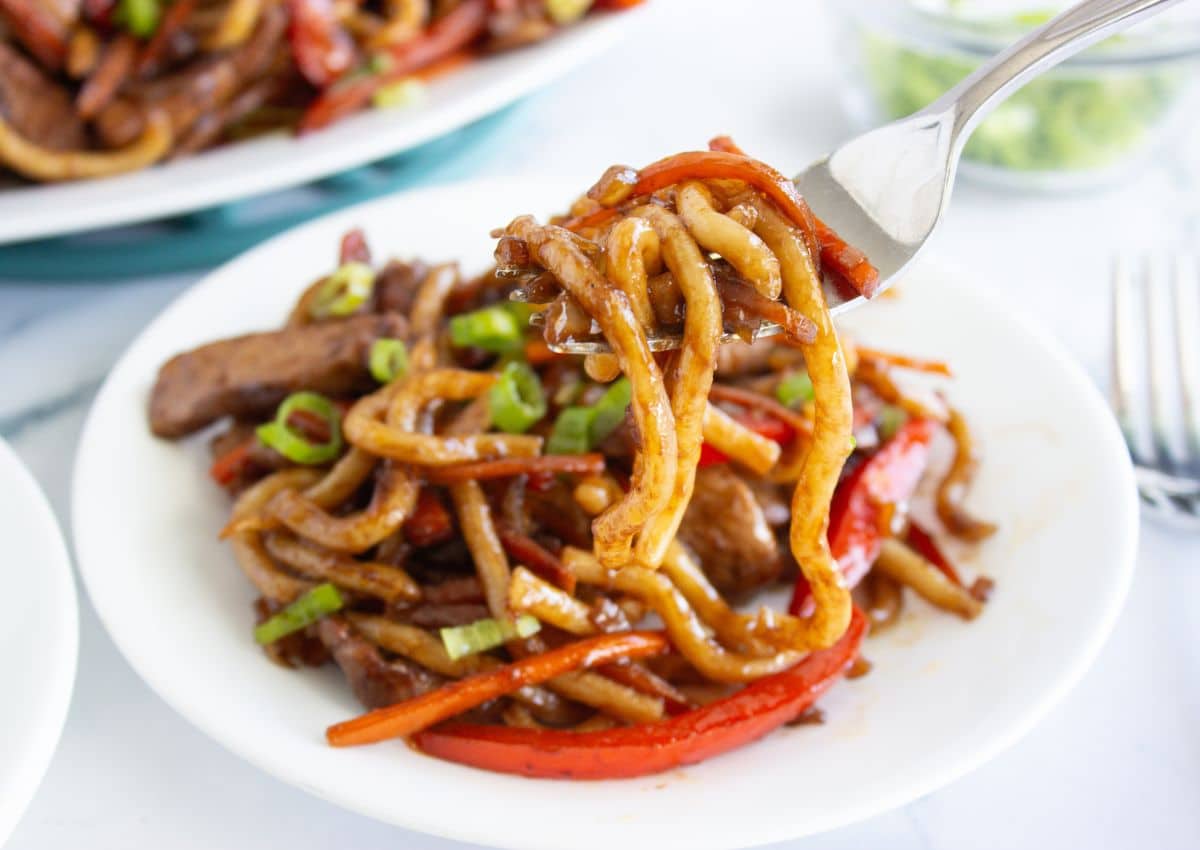 Bowl of pork lo mein on a table.