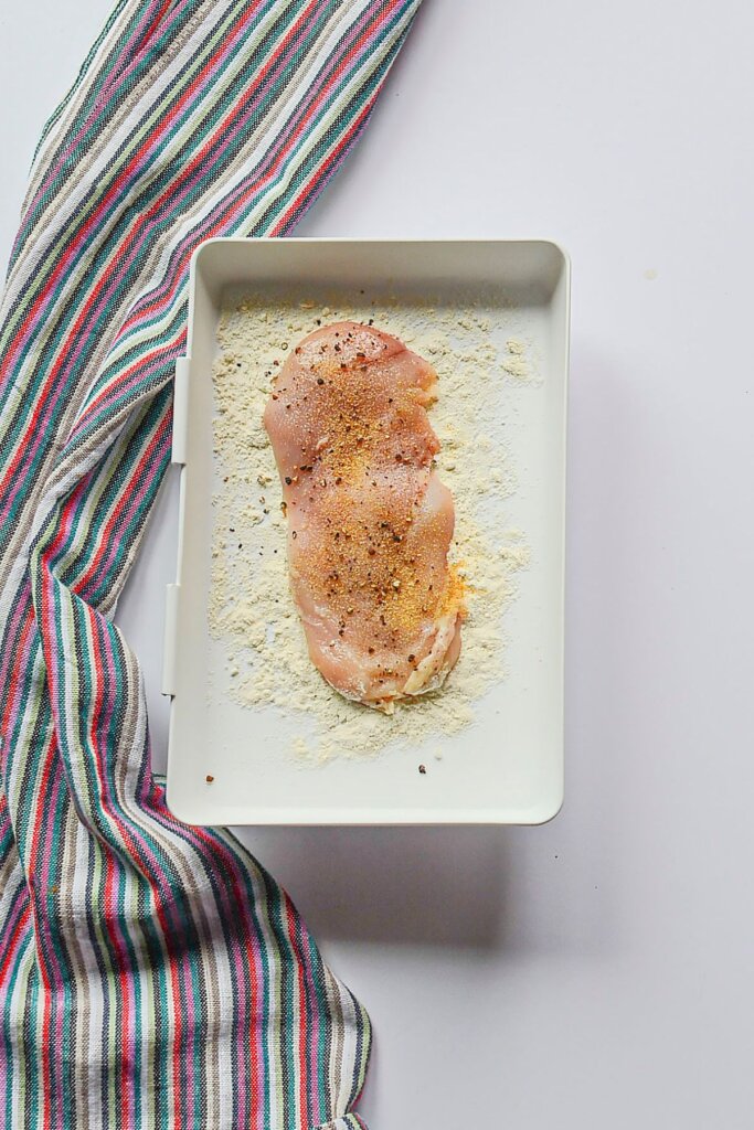 Chicken being dredged in flour.