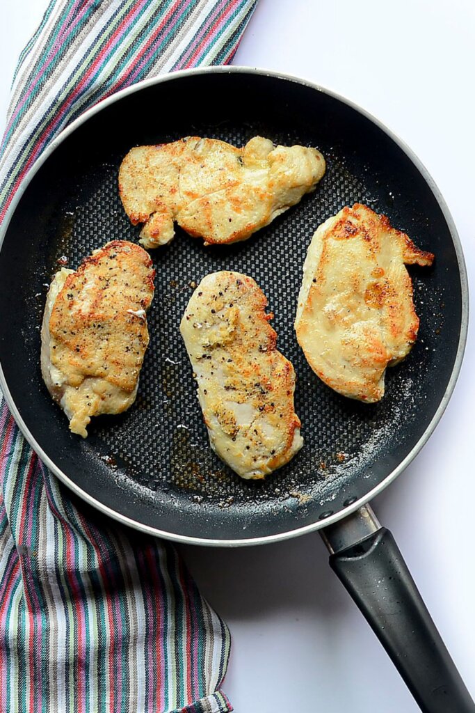 Chicken being seared in a skillet.