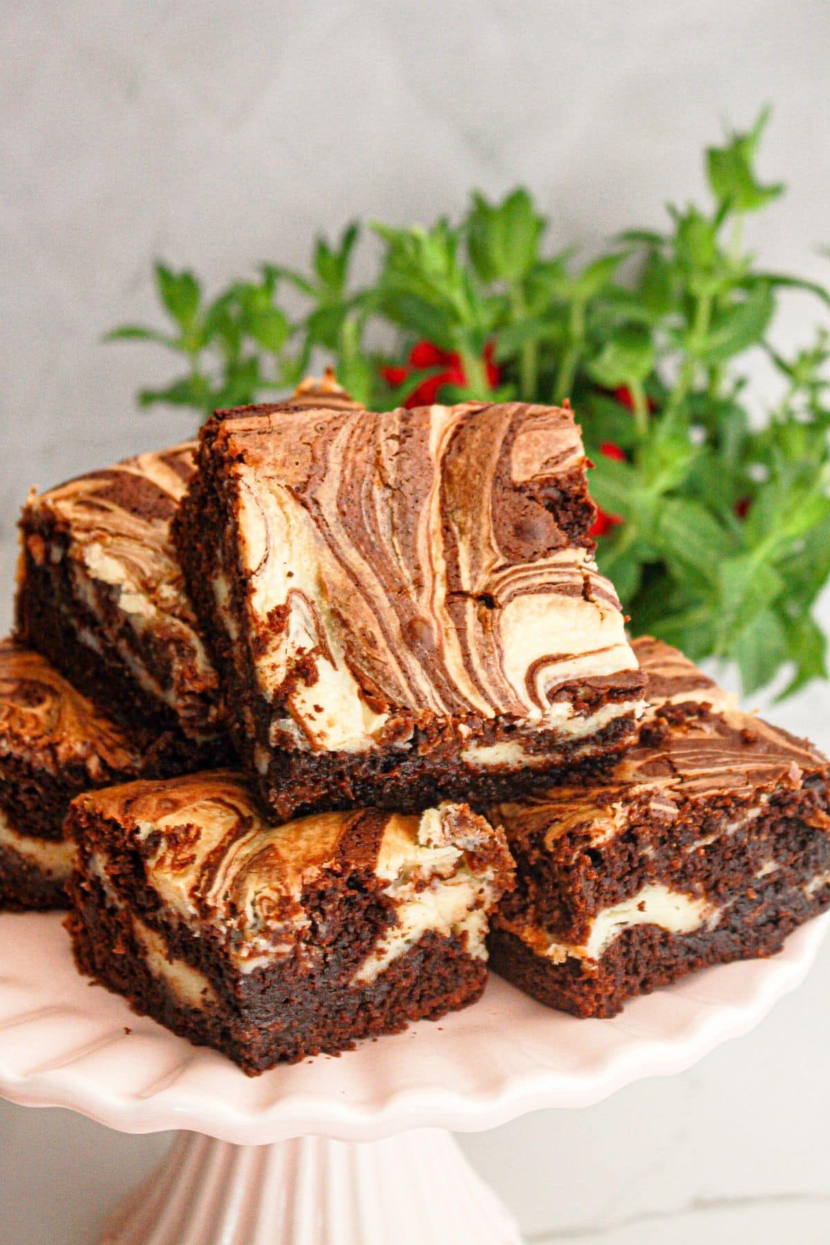 Cream cheese swirl brownies stacked on a cake stand.