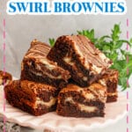 Cream cheese swirl brownies stacked on a cake stand.