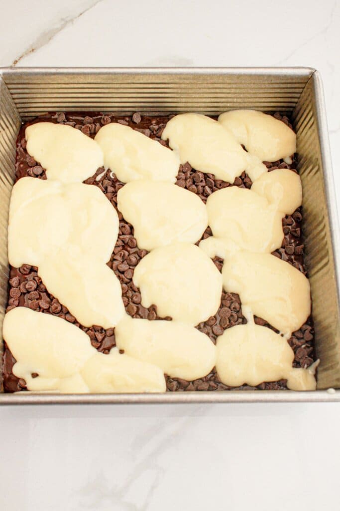 Cream cheese being added to the top of batter in a baking dish.