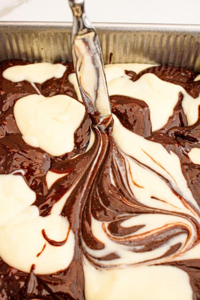 Brownies being swirled in a baking pan.