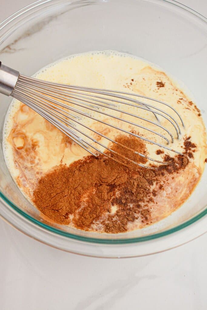 Eggs and seasonings being mixed in a glass bowl.