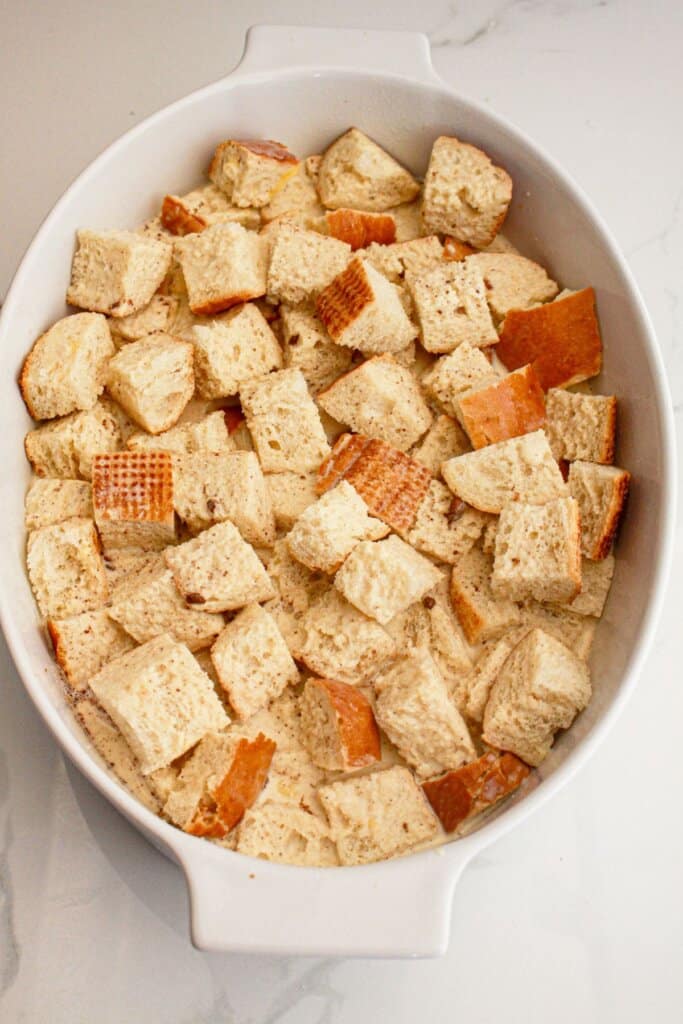 Bread pieces coated in custard in a baking dish.