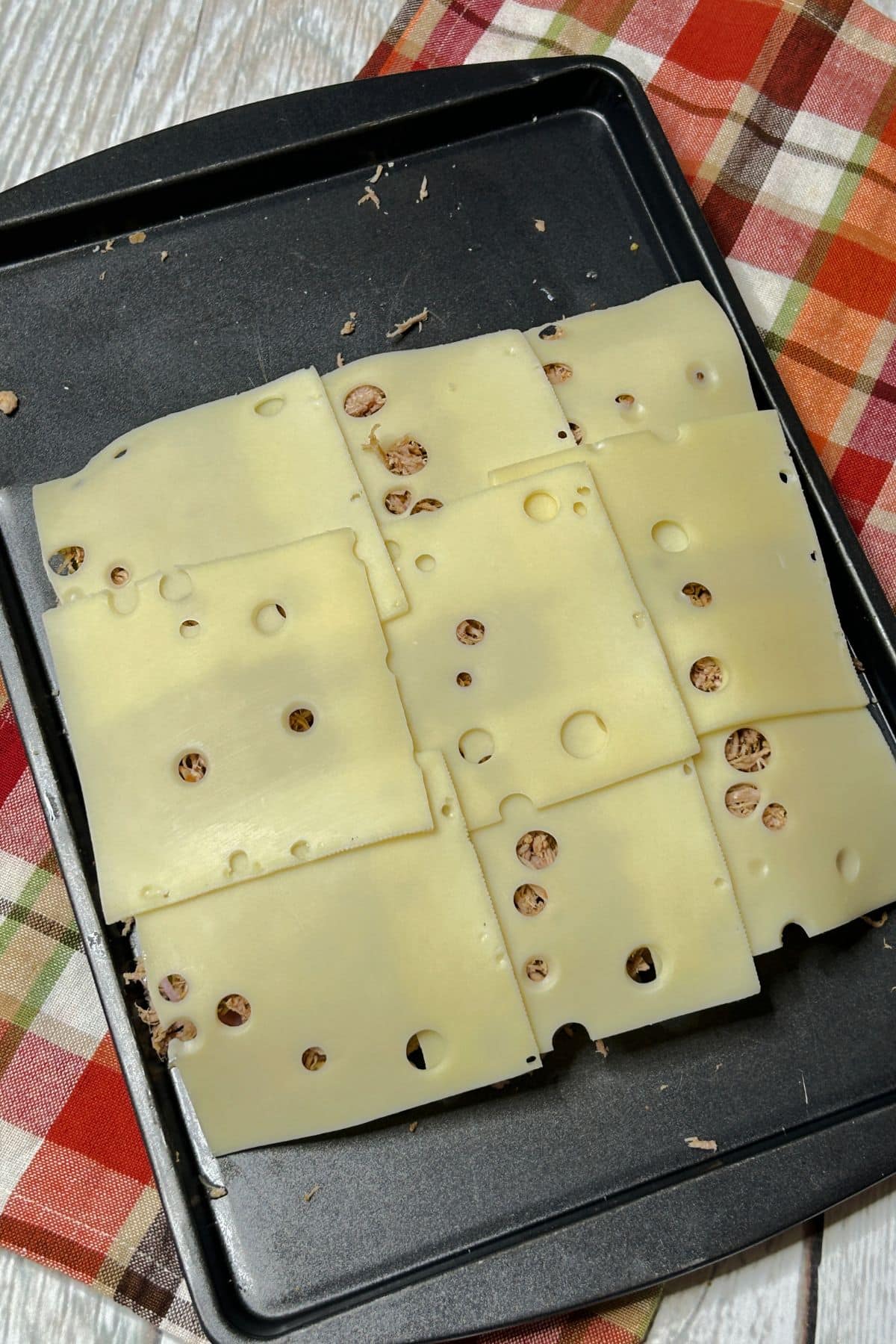 Cheese being placed on top of sandwiches.