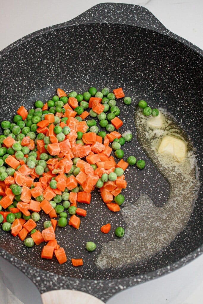 Butter, carrots and peas in a skillet.