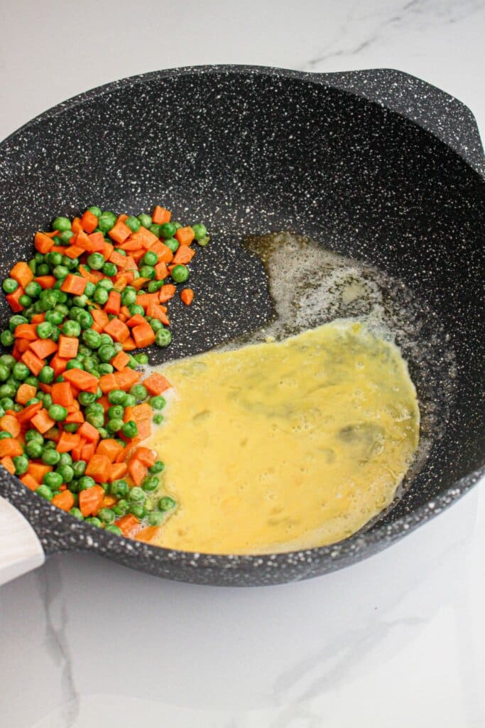 Egg, peas, and carrots in a skillet.