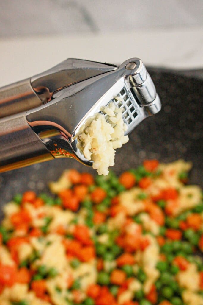 Garlic being minced in a garlic press.