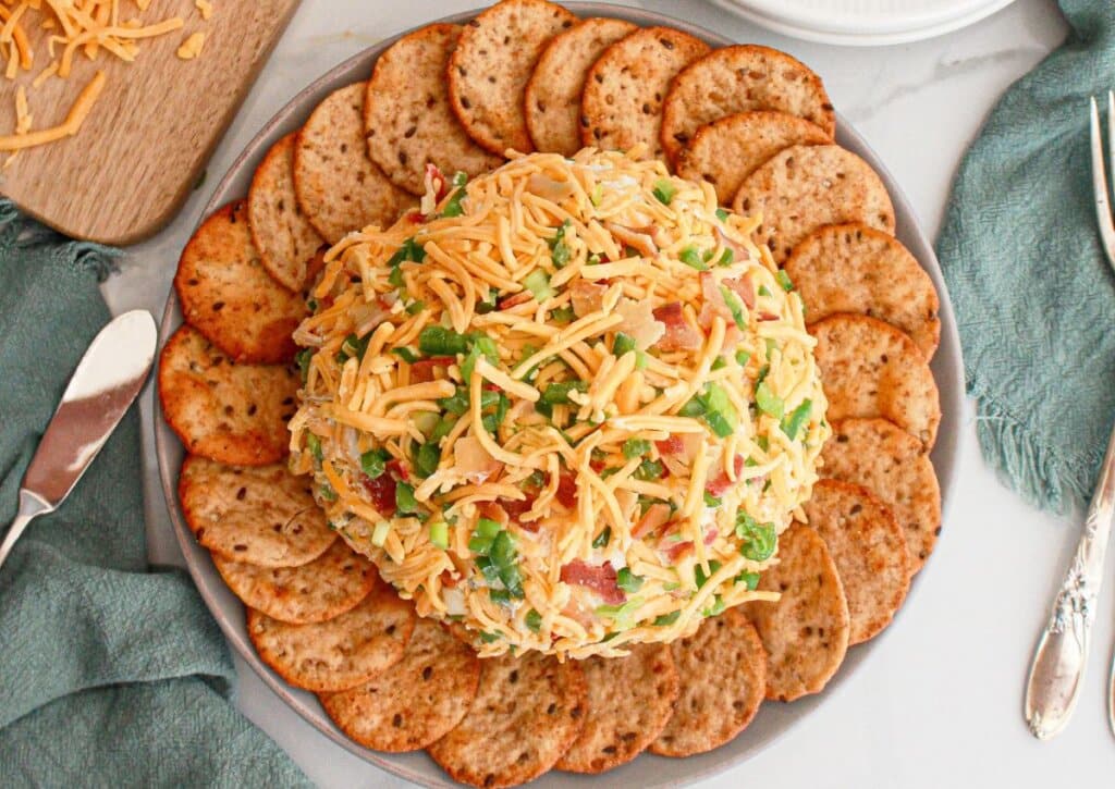 Cheese ball surrounded by crakckers on a platter.