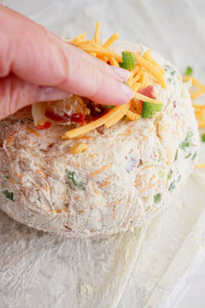 Bacon, cheese, and green onions being pressed onto surface.
