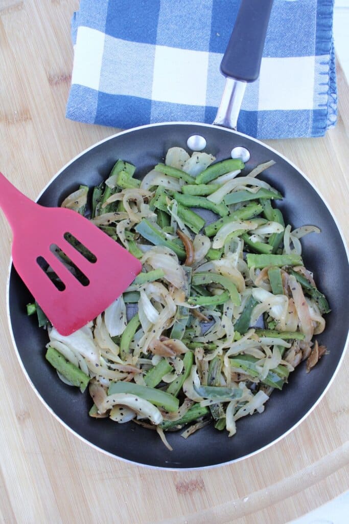 Peppers and onions being cooked in a skillet.