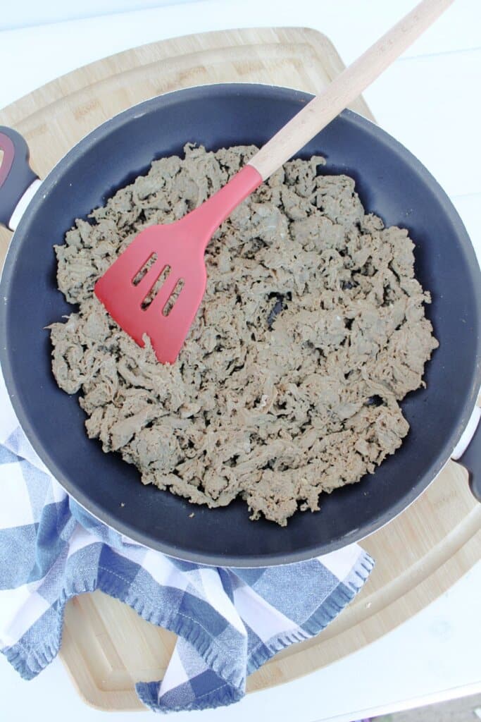 Shaved beef being cooked in a skillet.