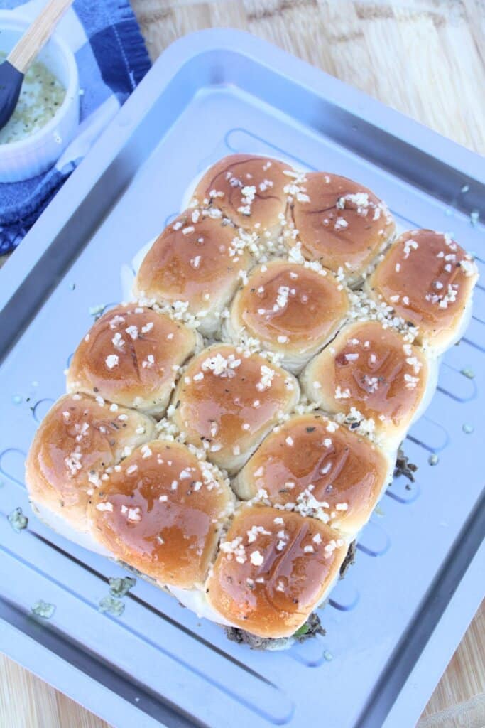 Seasoned butter being brushed on top of rolls.