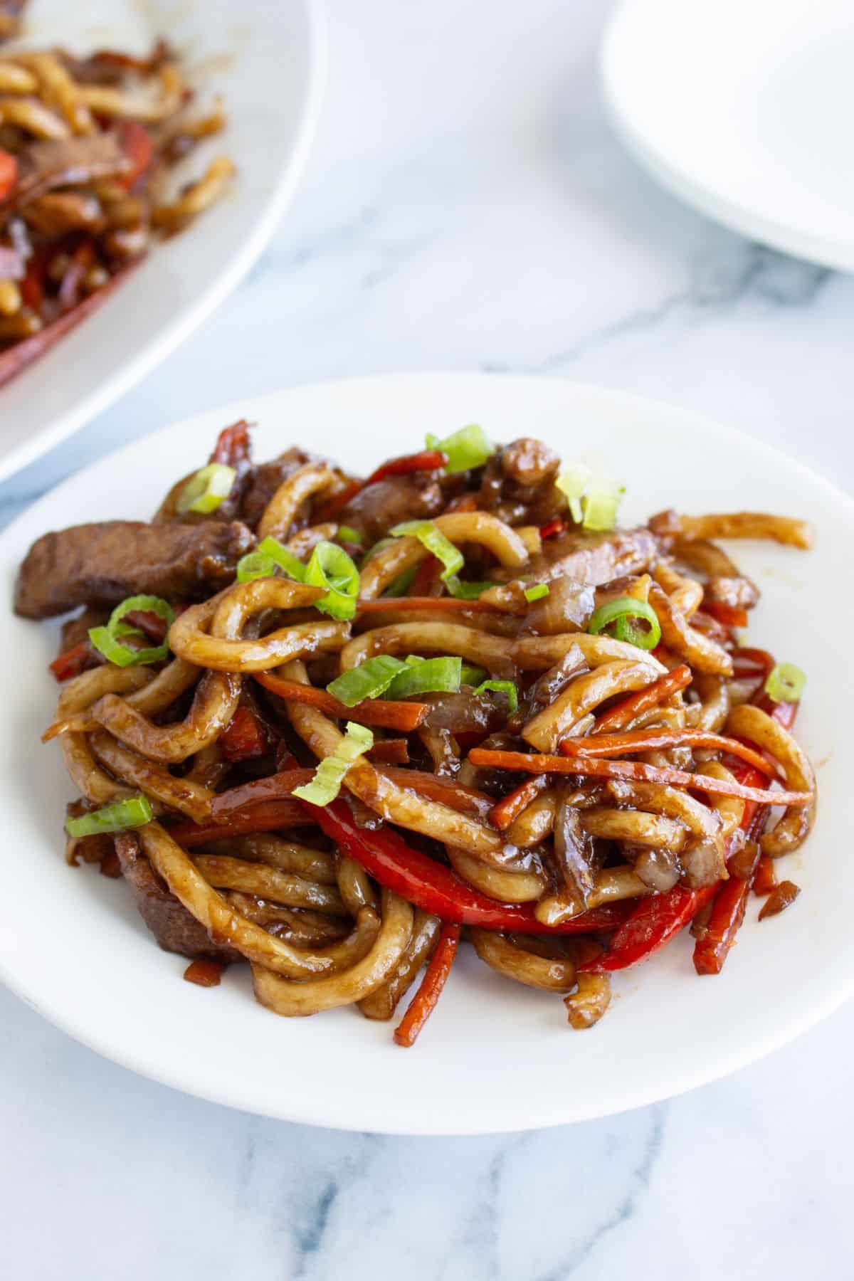 Bowl of pork lo mein on a table.
