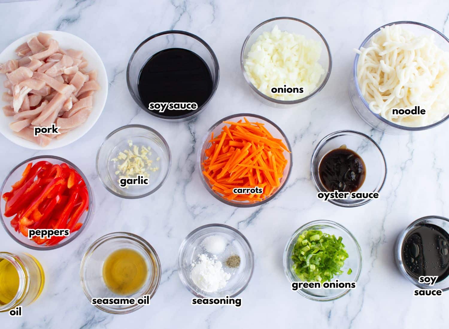 Bowls of ingredients for pork lo mein on a counter.