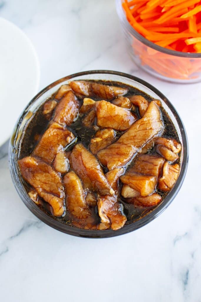 Pork tenderloin slices in a marinade.