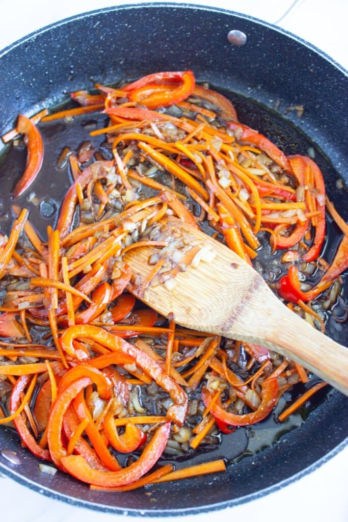 Carrots, onions, and bell peppers in a skillet.