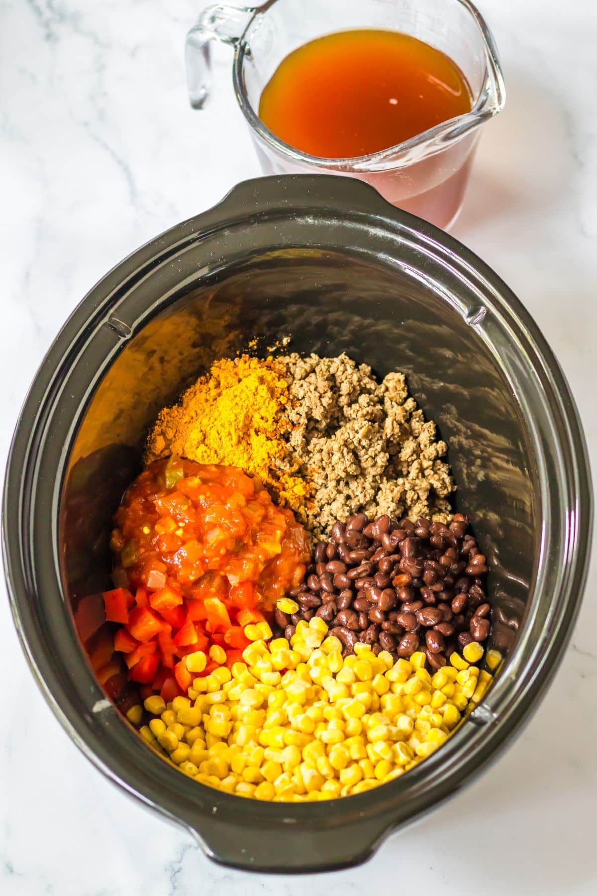 Beef, tomatoes, salsa, corn, beans,and seasoning being added to slow cooker.