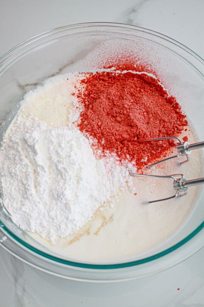 Frosting being mixed in a glass mixing bowl.