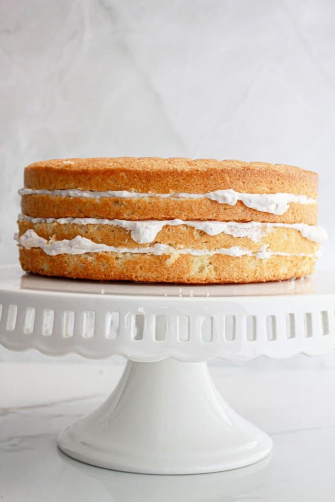 Cakes being frosted on a cake stand.