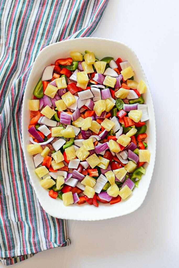 Pineapples, bell peppers, and onions in a baking dish.