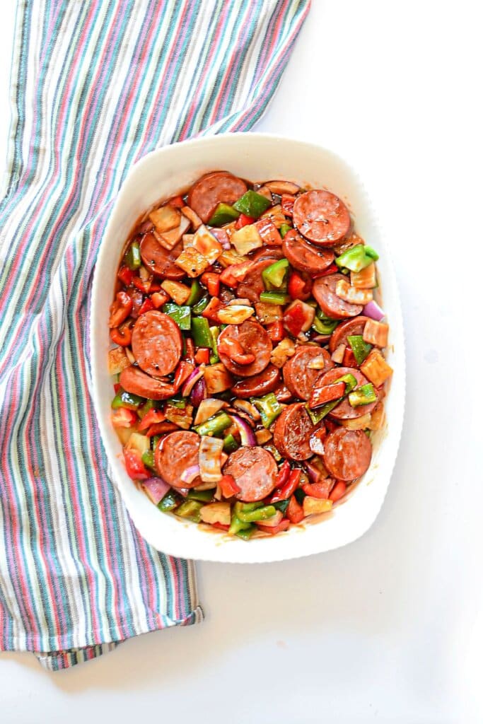 Baking dish full of kielbasa and vegetables.