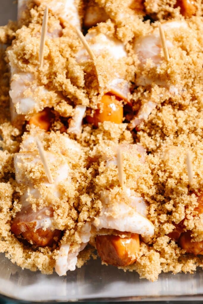 Brown sugar being sprinkle over lil hotdogs.
