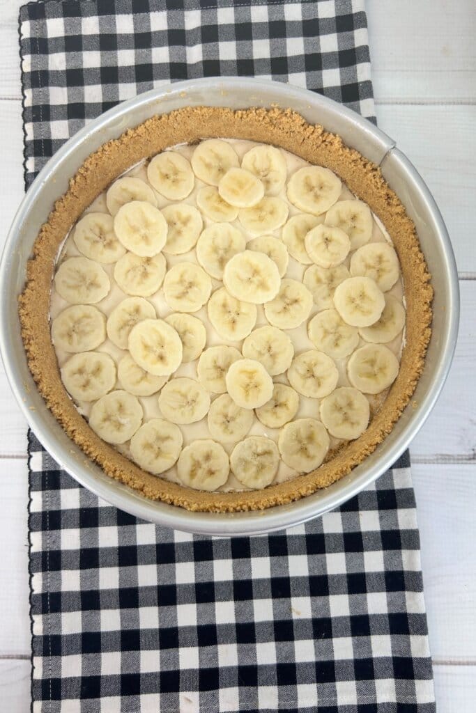 Banana slices being layered in a springform pan.