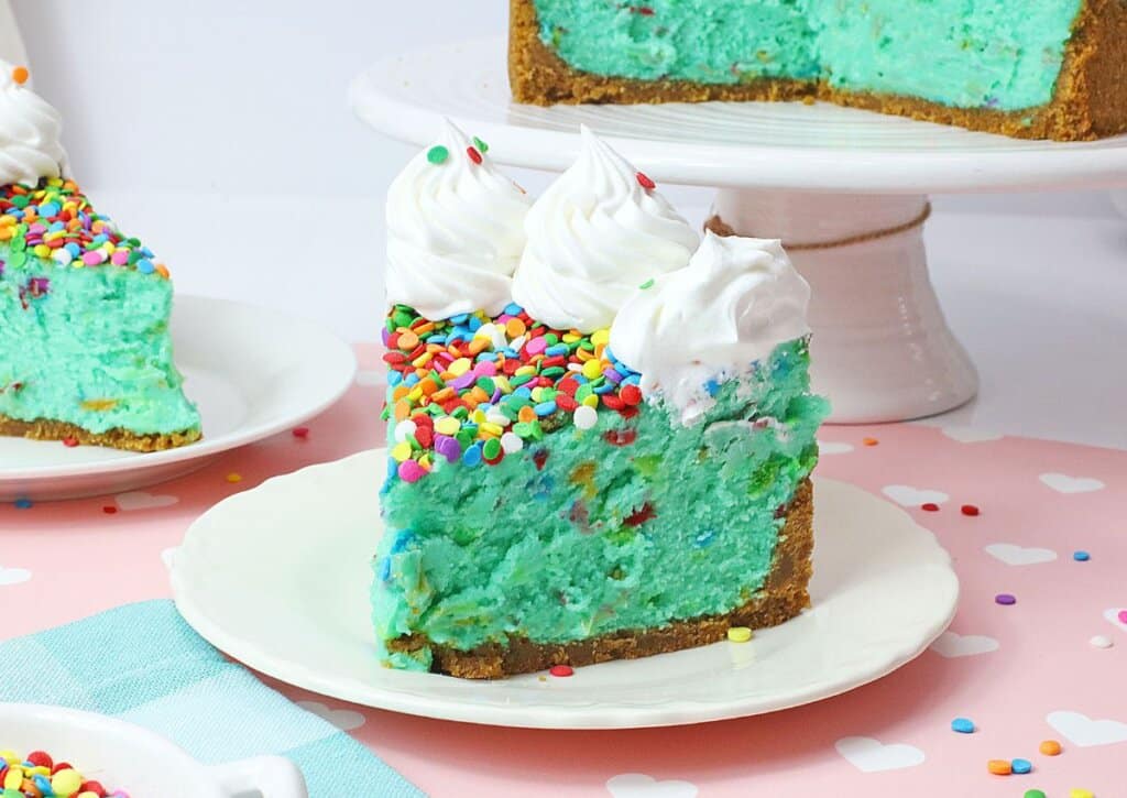 Slice of birthday cake cheesecake on a plate.