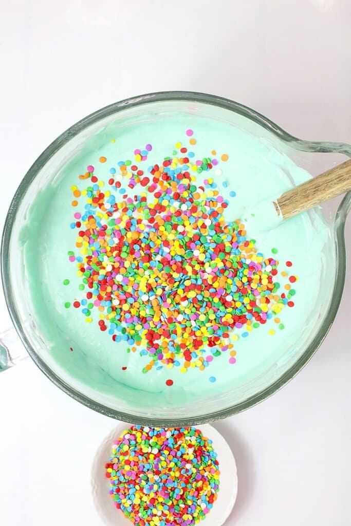 Sprinkles added to cheesecake batter in a mixing bowl.