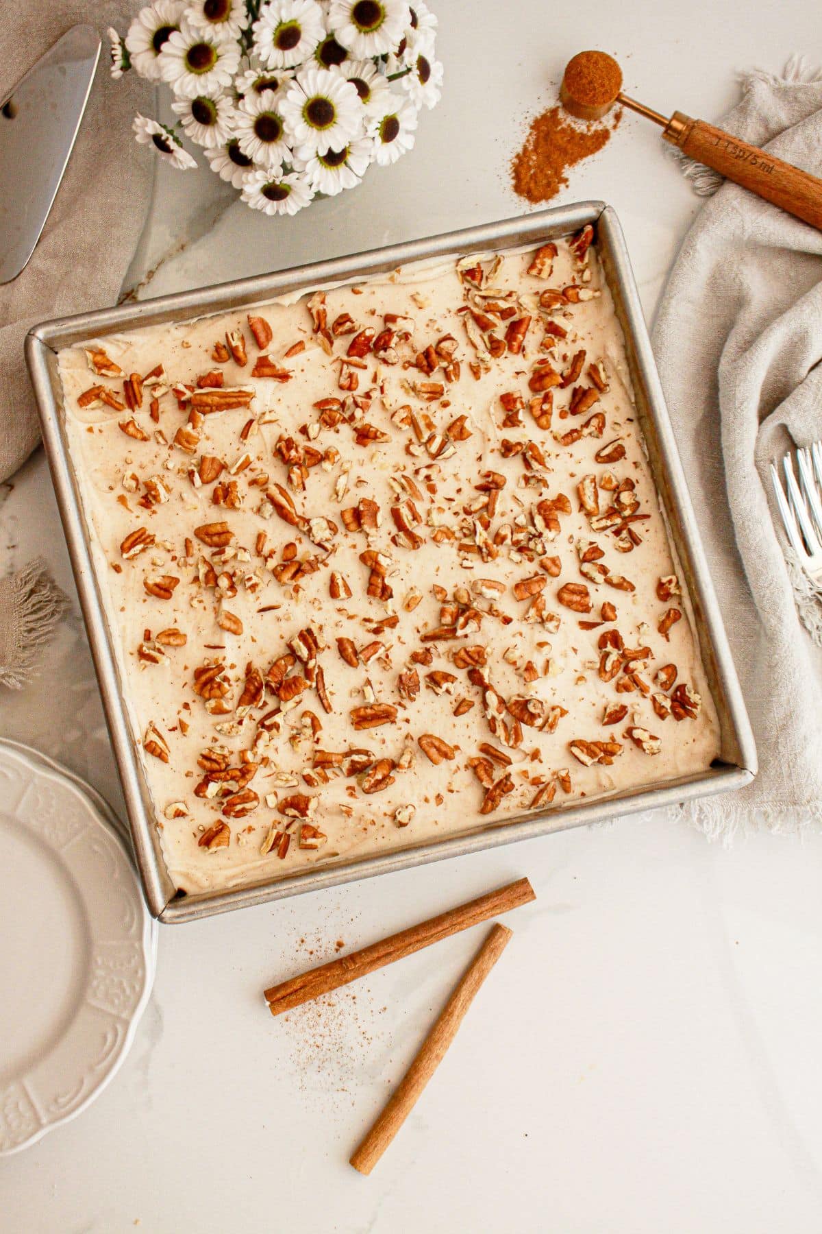 Carrot cake blondies topped with chopped pecans in a baking dish.